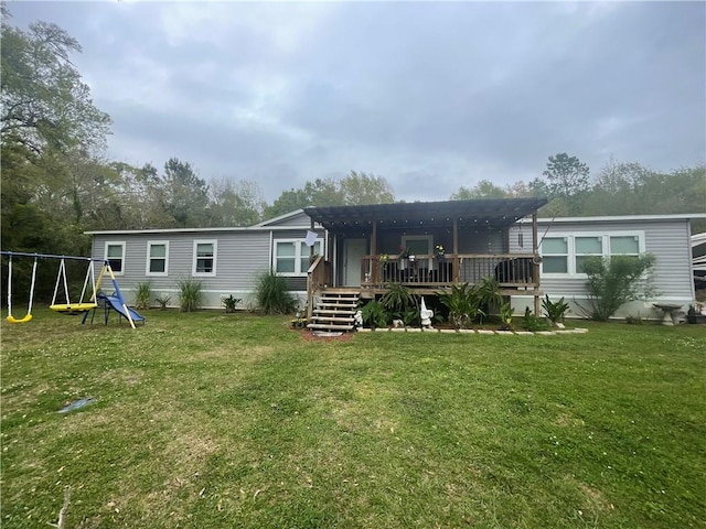 back of house with a wooden deck, a yard, and a playground