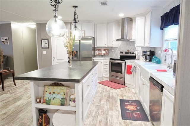 kitchen with a kitchen island, white cabinets, appliances with stainless steel finishes, wall chimney exhaust hood, and tasteful backsplash