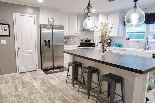 kitchen with stainless steel appliances, backsplash, white cabinetry, and decorative light fixtures