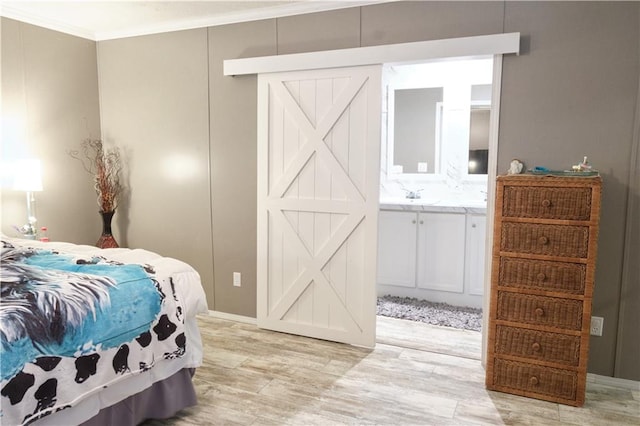 bedroom featuring connected bathroom, light hardwood / wood-style floors, sink, and ornamental molding