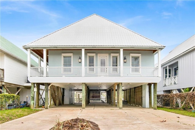 coastal home with a carport, covered porch, driveway, and stairs