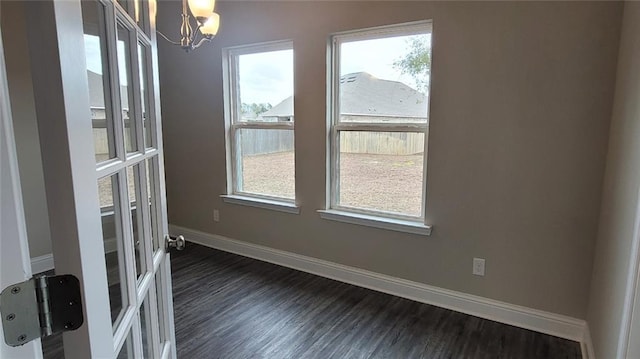 unfurnished room with an inviting chandelier and dark wood-type flooring