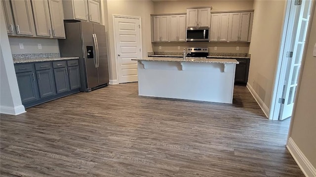 kitchen featuring stainless steel appliances, dark hardwood / wood-style flooring, a kitchen breakfast bar, and gray cabinetry