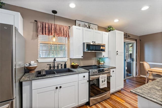 901 La Mothe Pl, Dauphin Island, AL 36528 - kitchen with light wood-type flooring, dark stone countertops, appliances with stainless steel finishes, white cabinets, and a sink