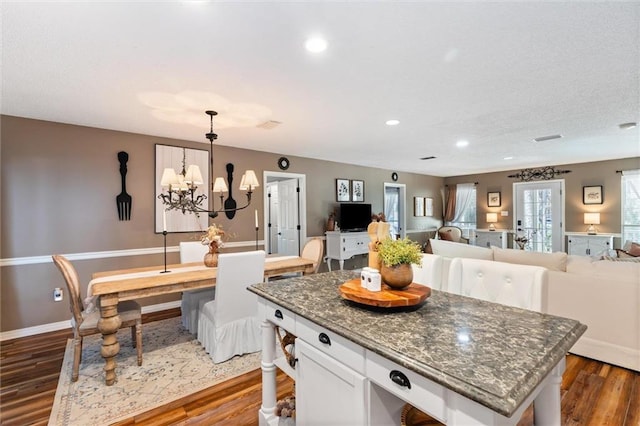 901 La Mothe Pl, Dauphin Island, AL 36528 - kitchen featuring a kitchen island, dark stone countertops, dark wood-style floors, a notable chandelier, and white cabinets