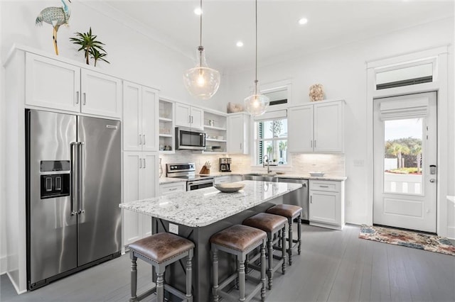 2455 Saltgrass Way, Orange Beach, AL 36561 - kitchen featuring appliances with stainless steel finishes, open shelves, decorative backsplash, a kitchen breakfast bar, and light stone countertops