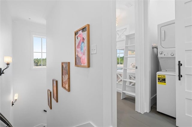 2455 Saltgrass Way, Orange Beach, AL 36561 - laundry area featuring stacked washer and clothes dryer, healthy amount of natural light, wood finished floors, and baseboards