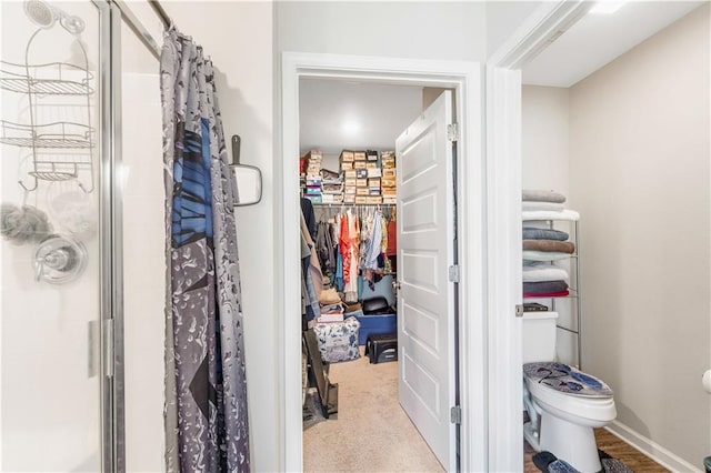 bathroom with a shower with shower door and toilet