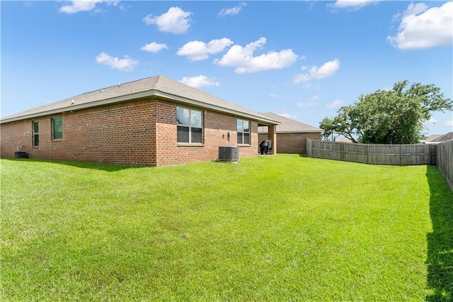 back of property with central AC unit and a lawn