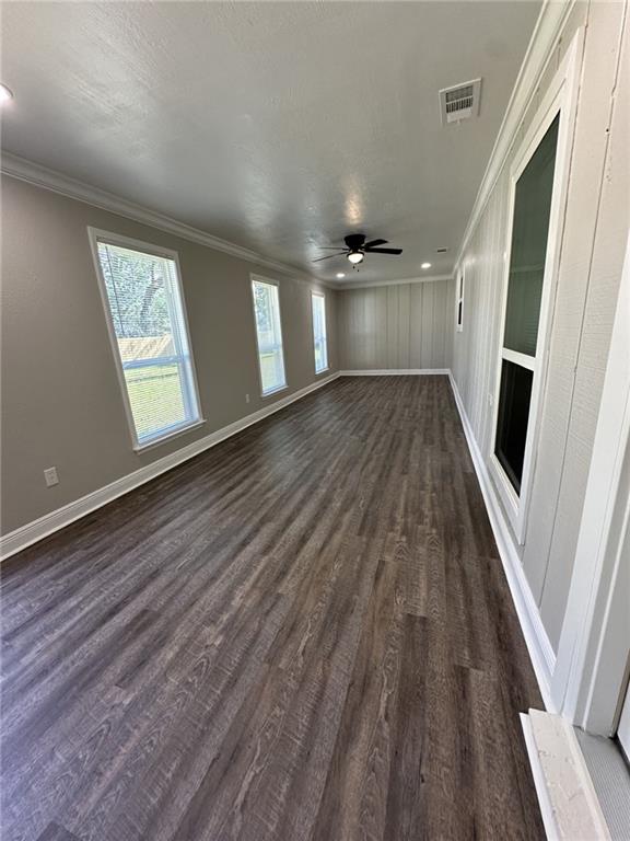 unfurnished living room featuring crown molding, dark hardwood / wood-style flooring, and ceiling fan