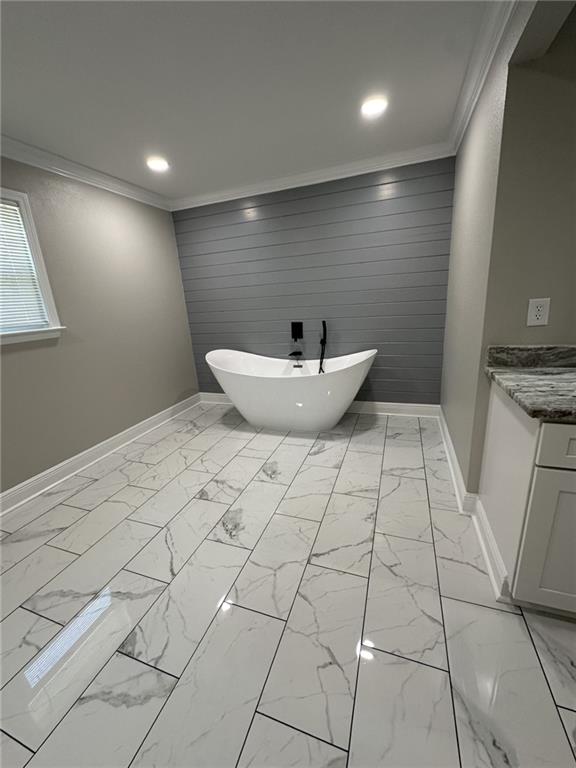 bathroom featuring a bathing tub, vanity, wood walls, and crown molding