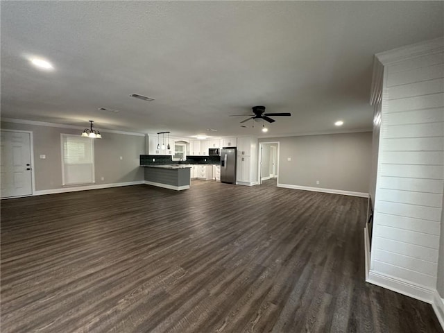 unfurnished living room with ceiling fan with notable chandelier, dark hardwood / wood-style floors, and ornamental molding