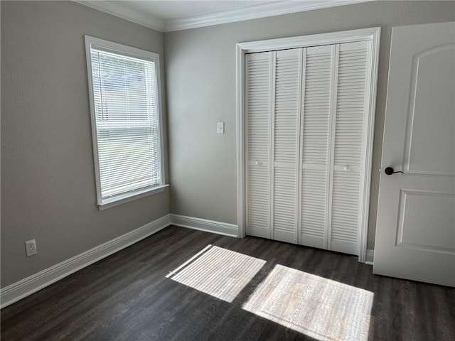 unfurnished bedroom with crown molding, a closet, and dark wood-type flooring