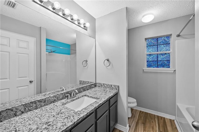 full bathroom featuring visible vents, toilet, a textured ceiling, wood finished floors, and vanity