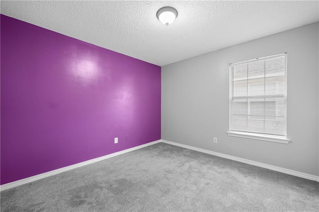 spare room featuring carpet flooring, baseboards, and a textured ceiling