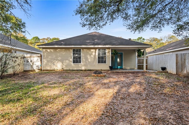 rear view of property with fence and an outdoor fire pit