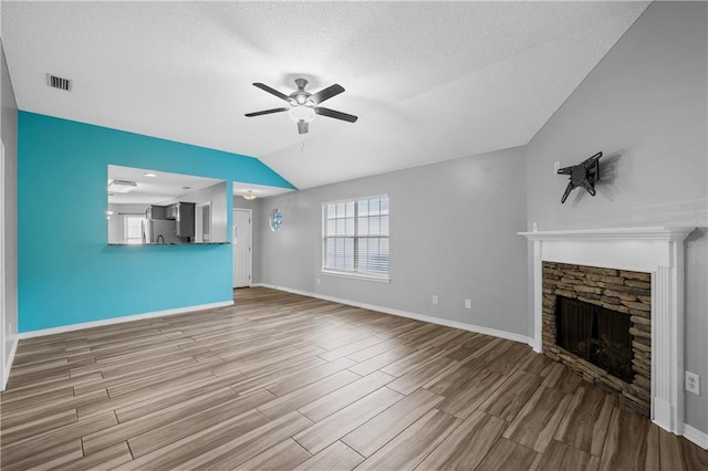 unfurnished living room featuring wood finished floors, a ceiling fan, visible vents, baseboards, and lofted ceiling