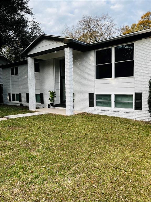 back of property with brick siding, a lawn, and a patio