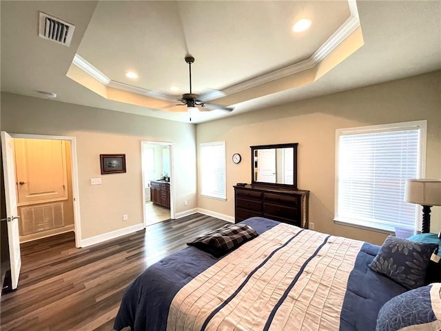 bedroom featuring ceiling fan, a raised ceiling, dark wood-type flooring, connected bathroom, and ornamental molding