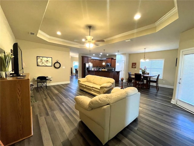 living room featuring a raised ceiling, ceiling fan with notable chandelier, dark hardwood / wood-style flooring, and ornamental molding