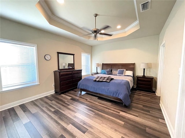 bedroom featuring dark hardwood / wood-style floors, a tray ceiling, crown molding, and ceiling fan