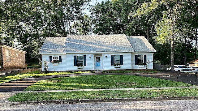 view of front of property featuring a shingled roof, a front lawn, and fence