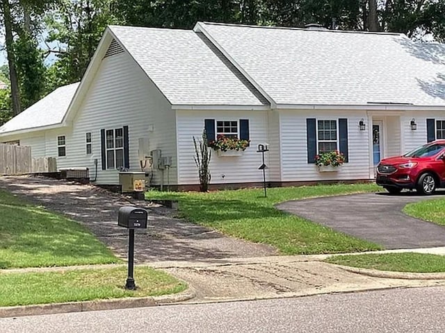 single story home featuring cooling unit, fence, a front lawn, and a shingled roof