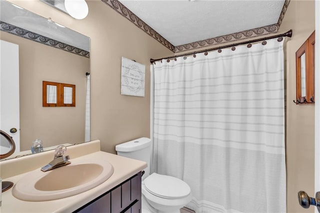 bathroom with vanity, curtained shower, toilet, and a textured ceiling