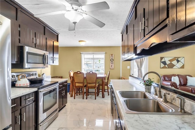 kitchen with dark brown cabinetry, sink, stainless steel appliances, and a textured ceiling