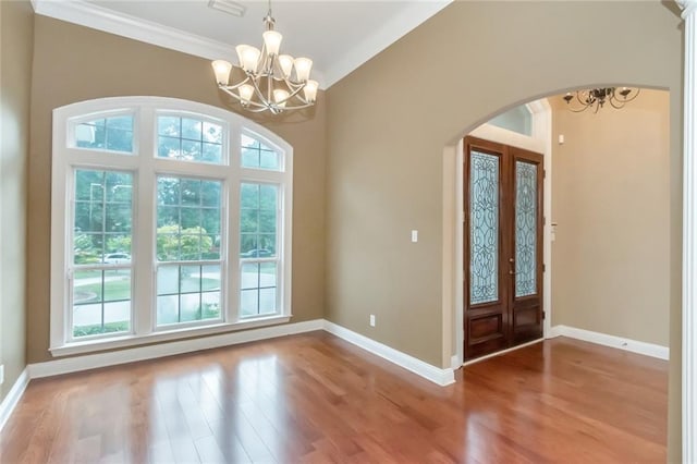 entrance foyer with crown molding, lofted ceiling, wood-type flooring, and a notable chandelier