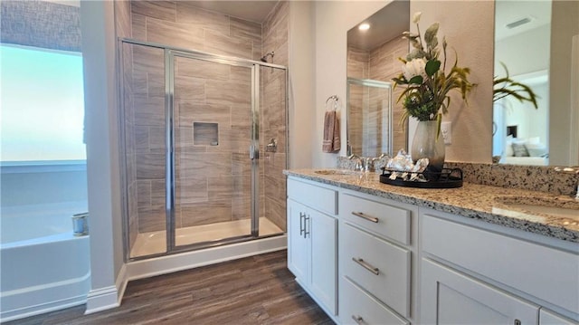 bathroom with a sink, double vanity, wood finished floors, and a shower stall