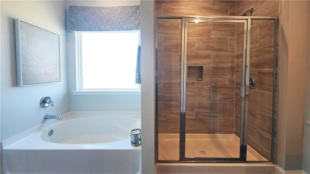 bathroom featuring a garden tub and a shower stall