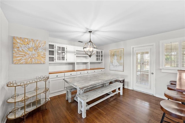 dining area with dark wood-type flooring, visible vents, baseboards, and a notable chandelier