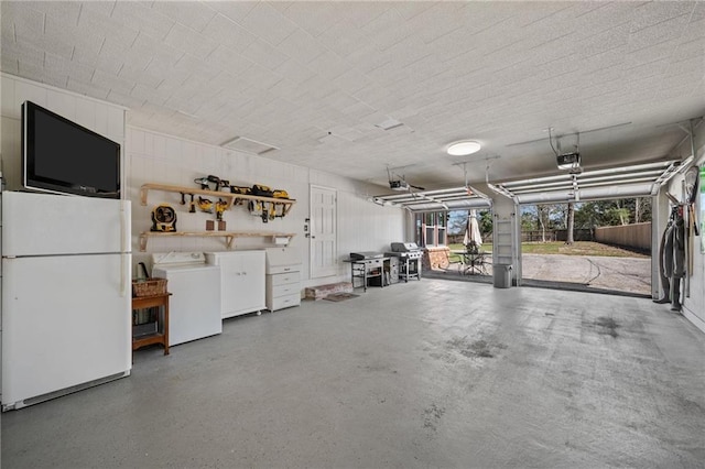 garage with a garage door opener, washer and clothes dryer, and freestanding refrigerator
