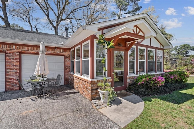 doorway to property featuring a garage and brick siding
