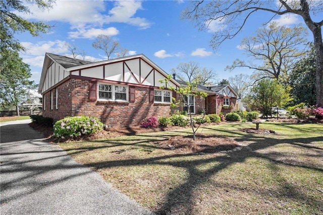 view of home's exterior with brick siding, driveway, board and batten siding, and a lawn