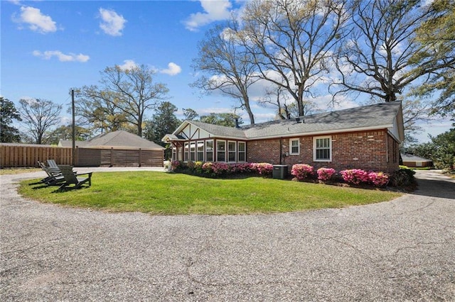 exterior space featuring a yard, brick siding, central air condition unit, and fence