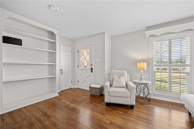 sitting room featuring built in features, baseboards, and wood finished floors