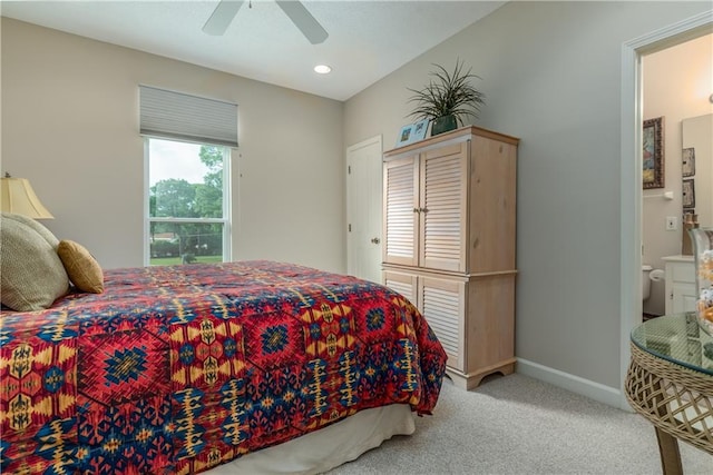 carpeted bedroom with ensuite bathroom and ceiling fan