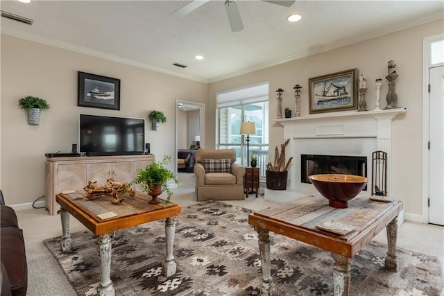 carpeted living room with ceiling fan, crown molding, and a fireplace