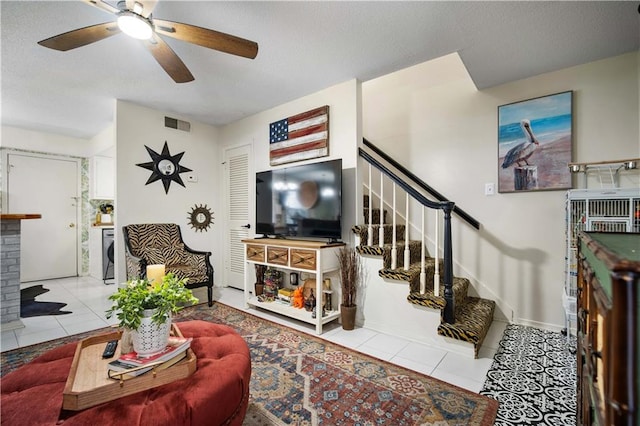 living room with a fireplace, light tile patterned floors, and ceiling fan