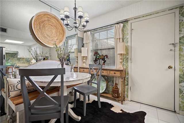 dining room with light tile patterned flooring, a textured ceiling, and a notable chandelier