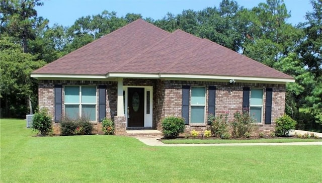 view of front of house featuring a front lawn, brick siding, and roof with shingles