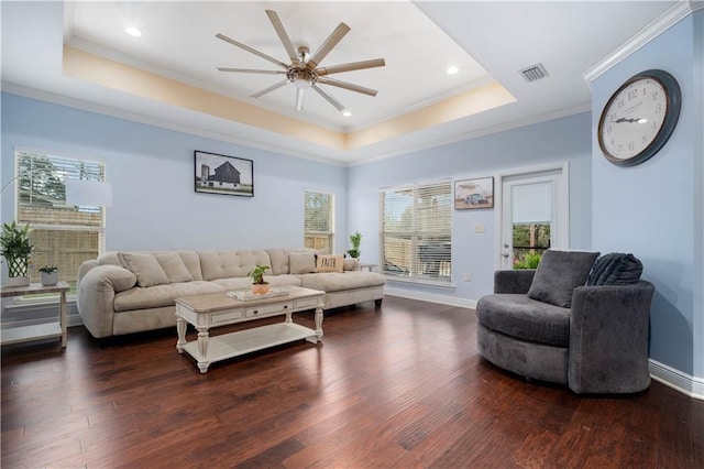 living room featuring a tray ceiling, visible vents, ornamental molding, and dark wood-style flooring