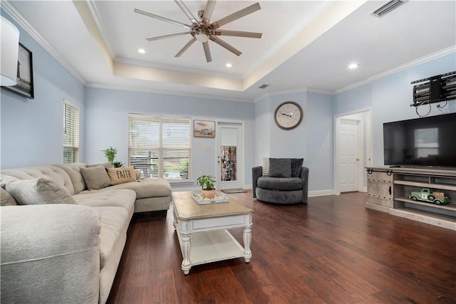 living area featuring a tray ceiling, crown molding, wood finished floors, and visible vents