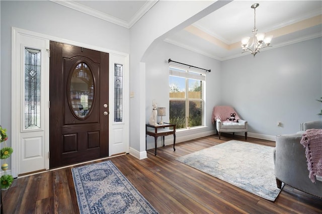 foyer entrance featuring a chandelier, baseboards, wood finished floors, and ornamental molding