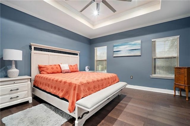 bedroom with a raised ceiling, dark wood-style floors, baseboards, and ornamental molding