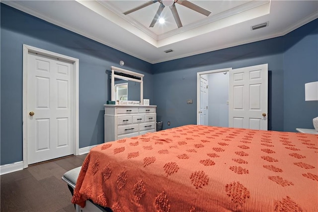 bedroom with visible vents, dark wood-type flooring, baseboards, crown molding, and a tray ceiling