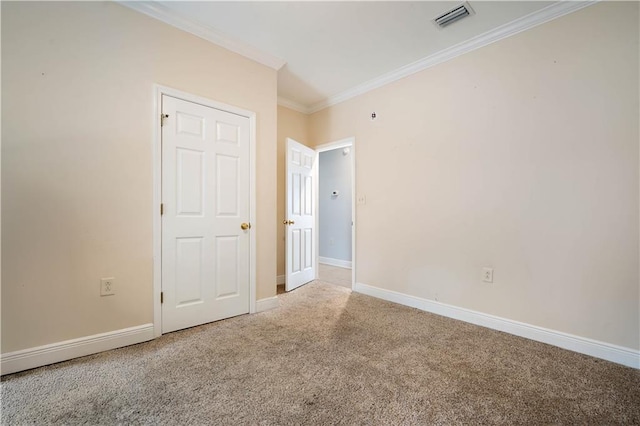 carpeted empty room featuring visible vents, baseboards, and crown molding