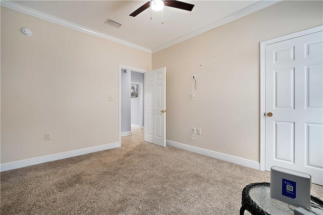 unfurnished bedroom with visible vents, light carpet, ornamental molding, baseboards, and ceiling fan